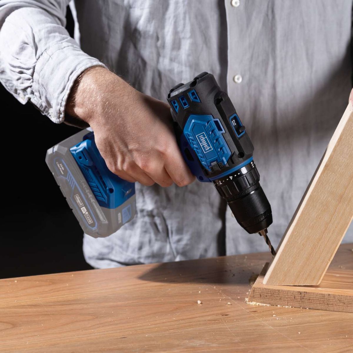 Scheppach Akku-Bohrschrauber mit Akku und Ladegerät in Gebrauch beim Holzbohren