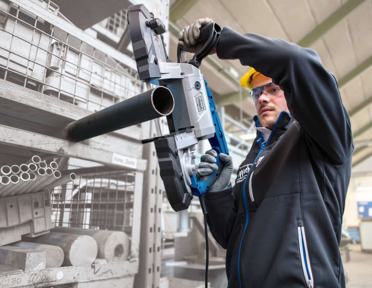 Ein Arbeiter bedient eine Bandsäge MBS1100 von Scheppach in einer Werkstatt. Die Säge wird zum Schneiden von Metallrohren verwendet.
