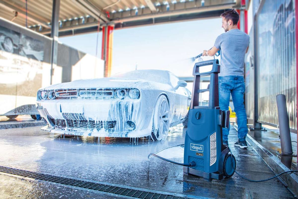 Ein Mann wäscht ein Auto mit dem Hochdruckreiniger HCE2400 von Scheppach. Der Reiniger hat einen blauen Griff und einen 5m Schlauch. Das Auto ist mit Schaum bedeckt.