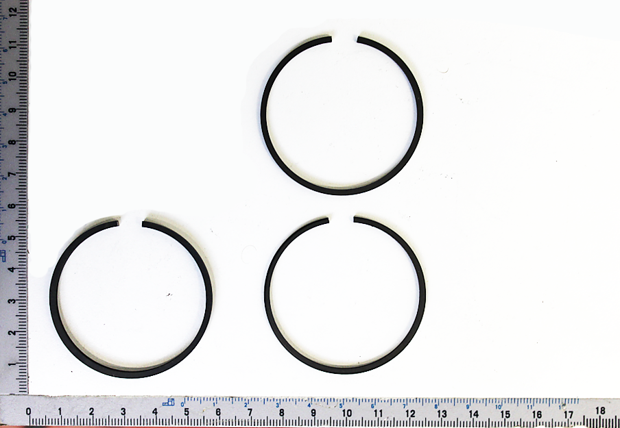 Kolbenringsatz mit drei Ringen, von oben fotografiert. Ein Ring ist in zwei Teile geteilt.