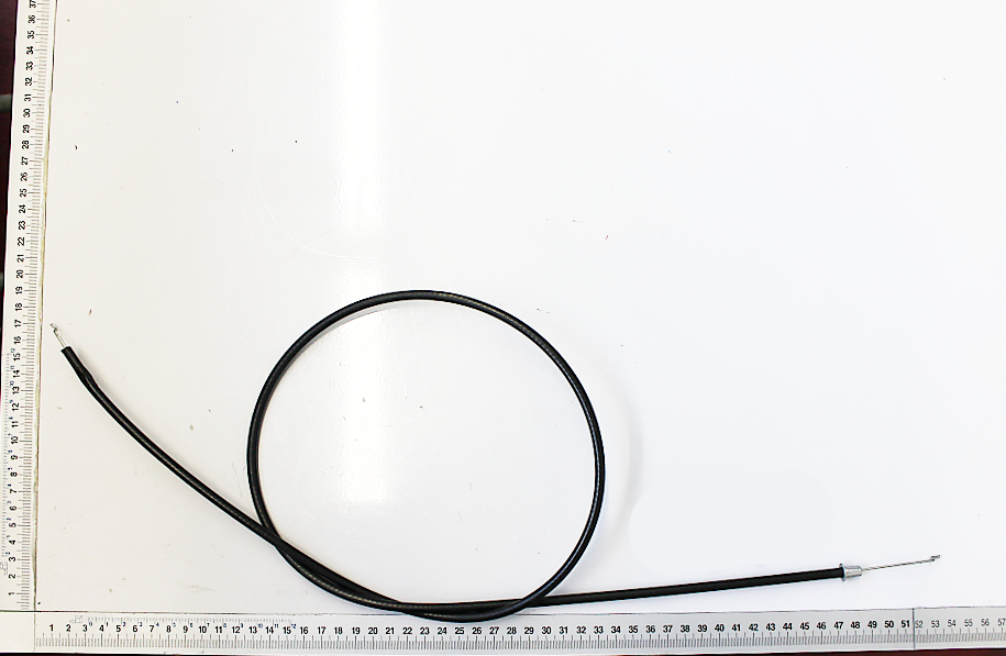 Ein Bowdenzug mit einem Messschieber im Hintergrund. Der Bowdenzug ist von links nach rechts ausgerichtet.