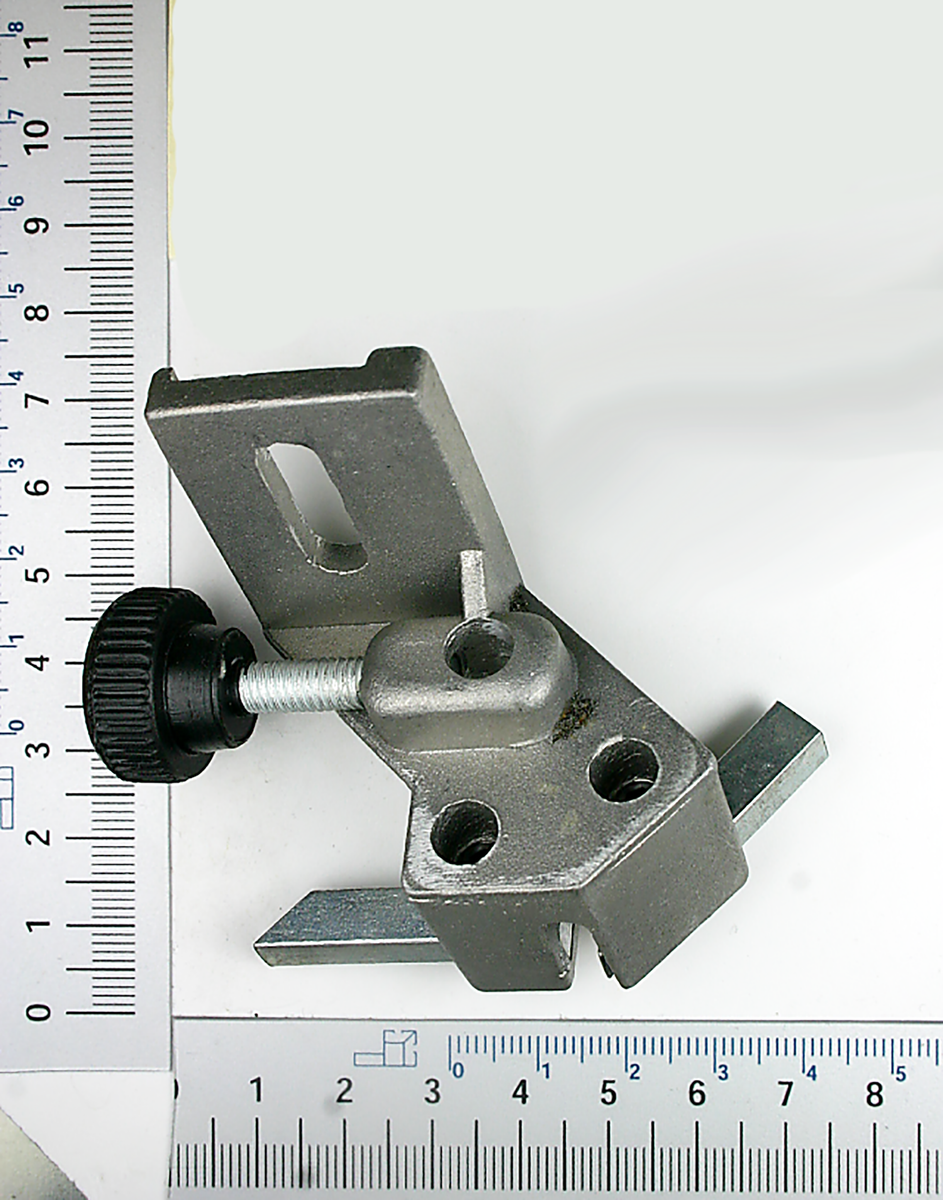 Bandführung unten Teil 67, 71-73 von Scheppach. Metallteil mit schwarzem Drehknopf und zwei Löchern. Gezeigt von der Seite.