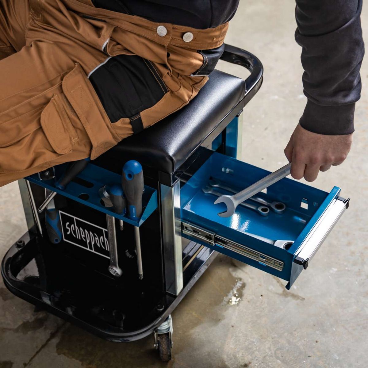 Der Scheppach 2in1 Werkstatthocker TW900 hat zwei Schubladen für Werkzeuge und einen gepolsterten Sitz. Die Schubladen sind leicht zugänglich und bieten viel Stauraum.