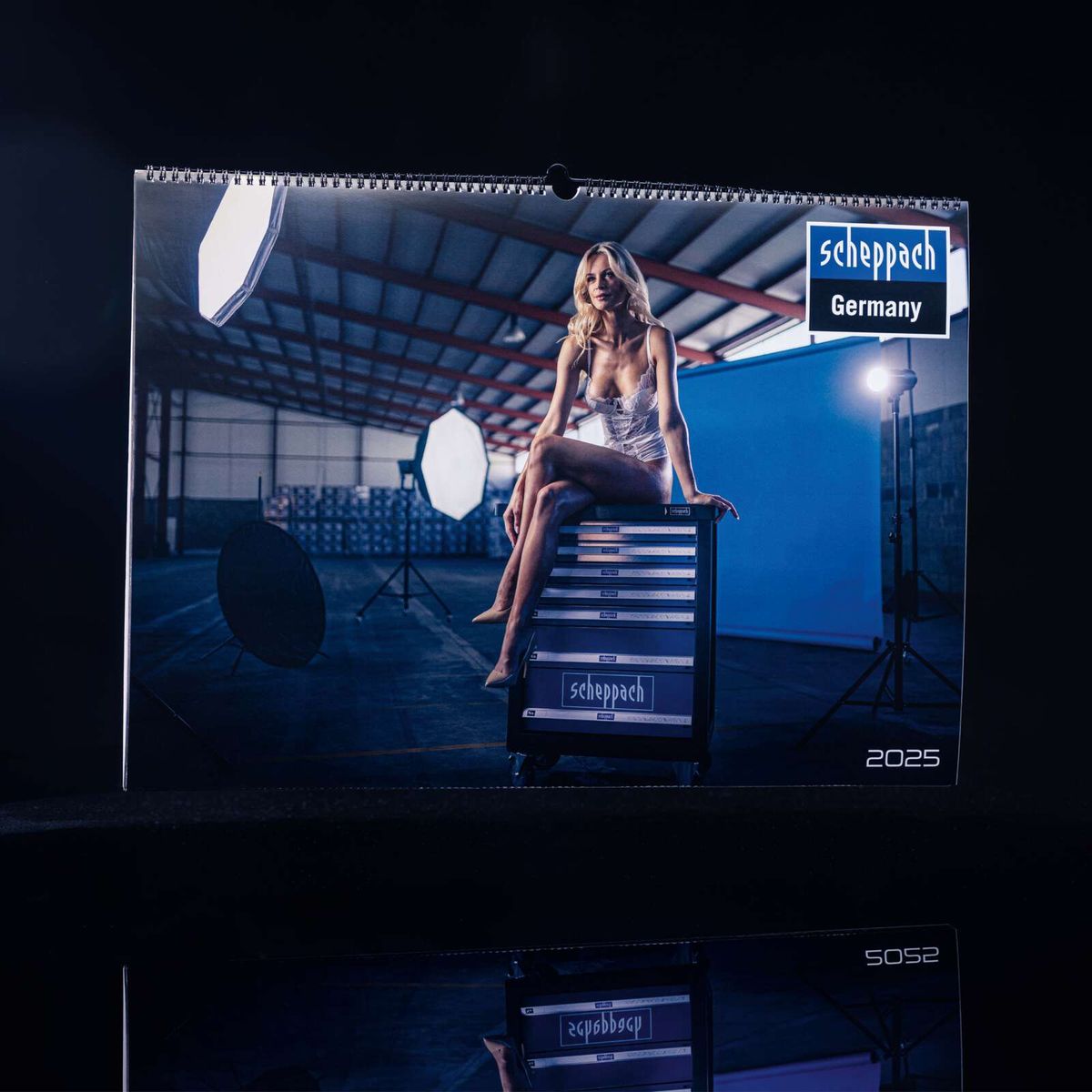 Jahreskalender 2025 von Scheppach. Eine Frau sitzt auf einem Scheppach Werkzeugkoffer. Scheppach Deutschland.