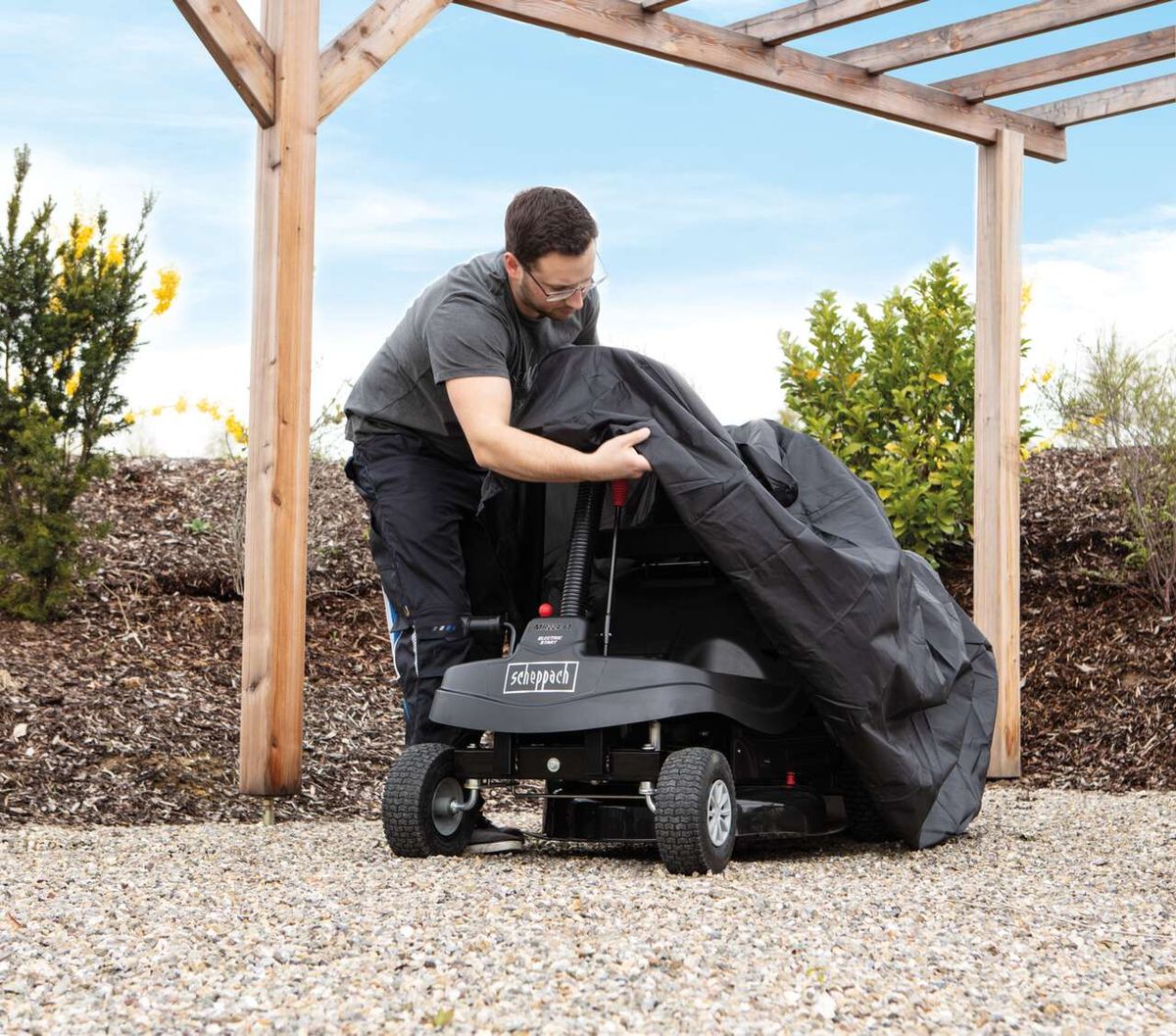 Scheppach Aufsitzrasenmäher mit Abdeckplane unter Aufstellschutz
