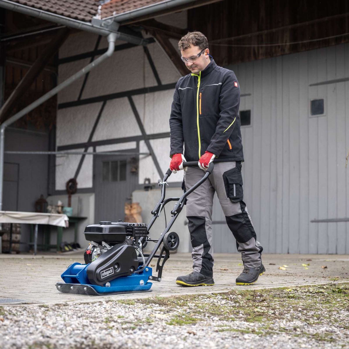 Mann mit Schutzausrüstung betreibt Scheppach-Gräsmaschine mit Handsteuerung