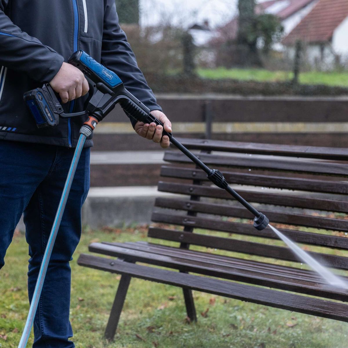 Person beim Einsatz eines Akku-Hochdruckreinigers mit Schlauch und Akku