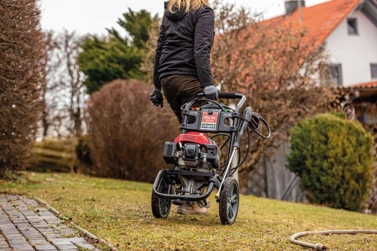 Person mit Scheppach Hochdruckreiniger auf dem Rücken, im Gartenbereich