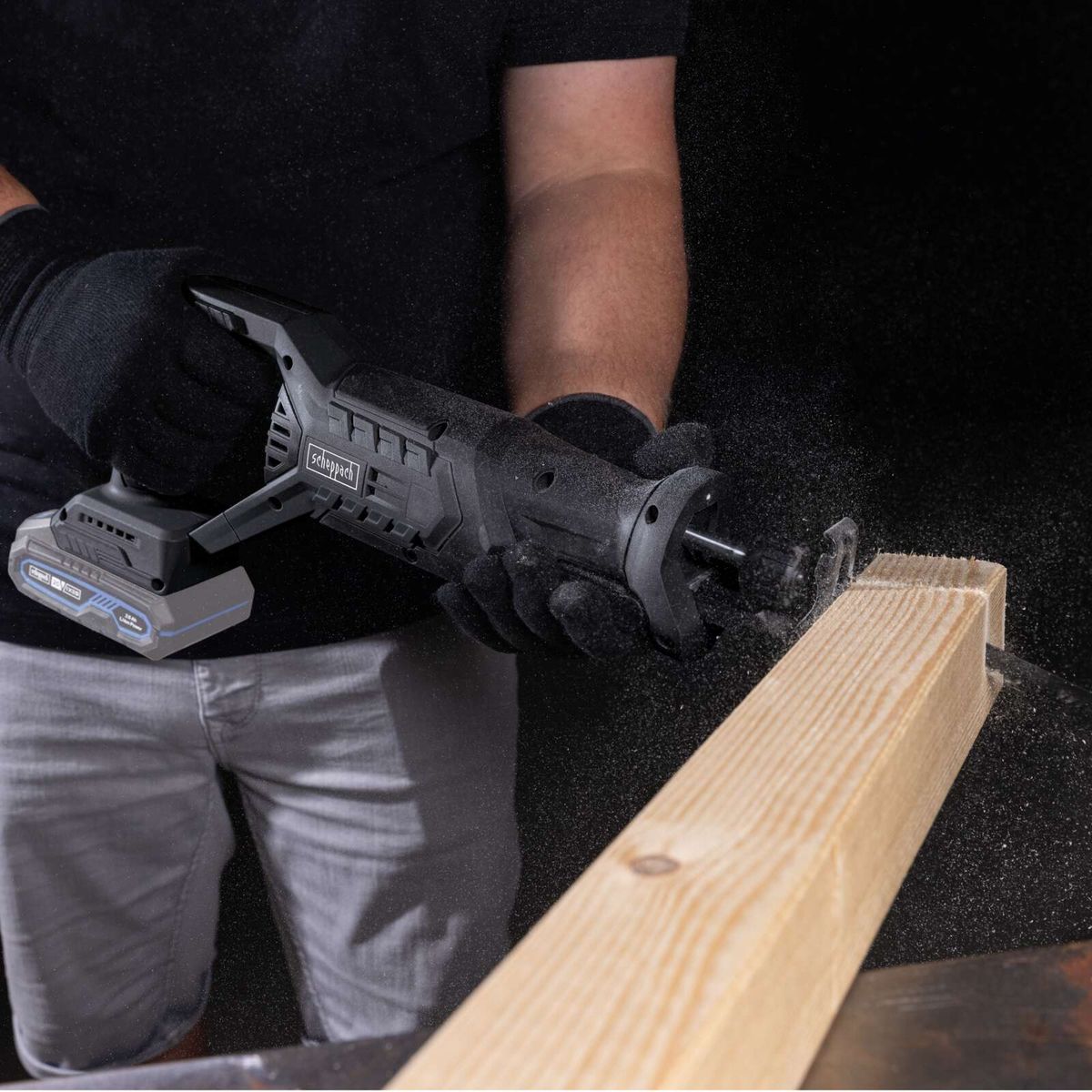 Scheppach Akku-Säbelsäge mit Akku und Werkzeug in Gebrauch, während Holz bearbeitet wird