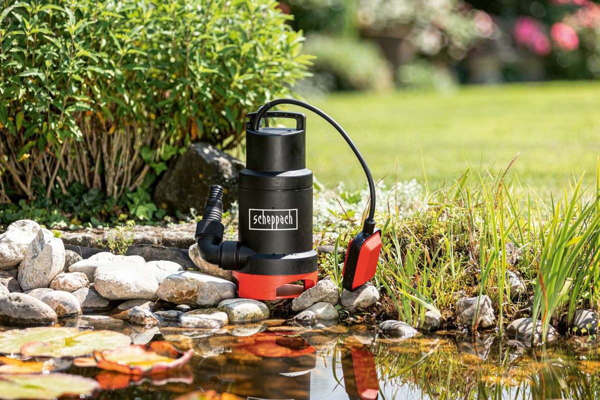 Scheppach Schmutzwassertauchpumpe SWP800-2 im Einsatz an einem Gartenteich mit Steinen und Pflanzen im Hintergrund.