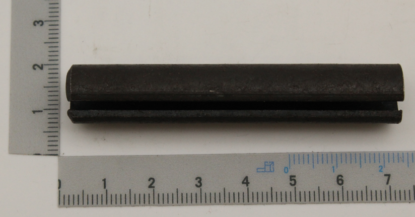 Eine schwarze Spannhülse 12x70 neben einem Lineal zur Größenveranschaulichung. Die Hülse liegt waagerecht auf dem Lineal.