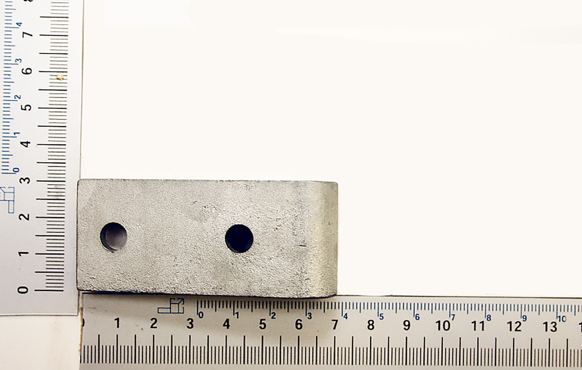 Ein weißes Schwenklager mit zwei Löchern, von oben fotografiert. Die Maße sind 6,5 cm lang und 3 cm breit.