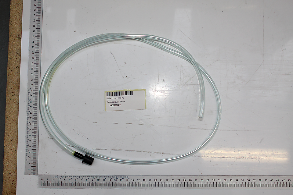 Wasserschlauch mit Verbinder, von oben fotografiert, mit Maßstab im Hintergrund.