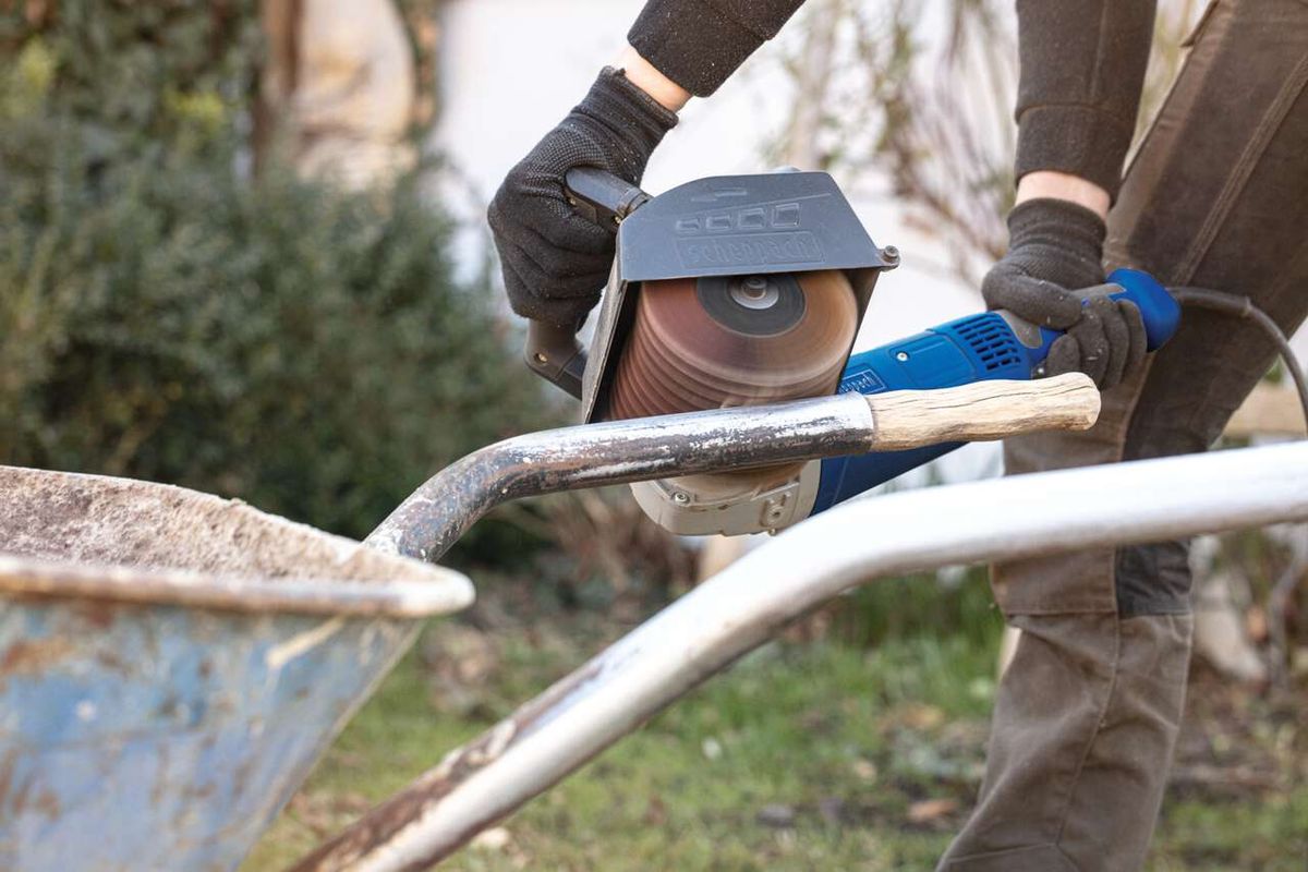 Scheppach Schleifstreifenbürste im Einsatz an einer MRS1300 Satiniermaschine. Die Bürste wird von einem Nutzer mit Handschuhen gehalten und bearbeitet Metall.
