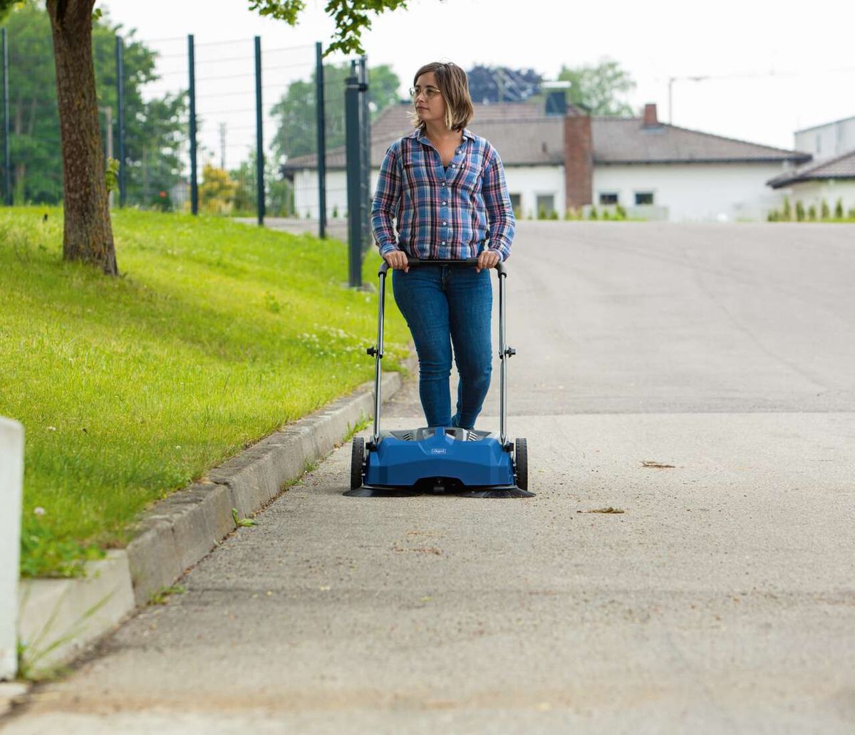 Person mit Handkurbel und Scheppach-Kehrmaschine auf dem Weg