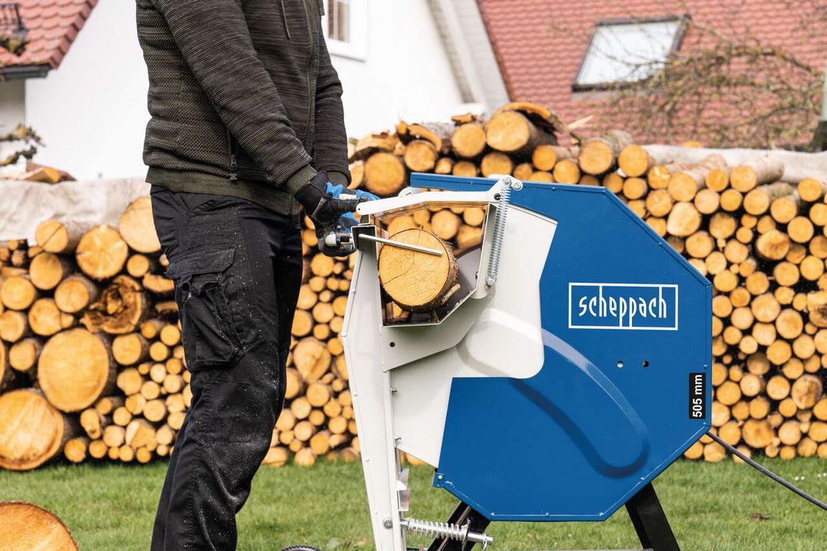 Wippsäge HS510 von Scheppach im Einsatz, Holzscheite werden zerkleinert. Im Hintergrund ein Holzstapel.