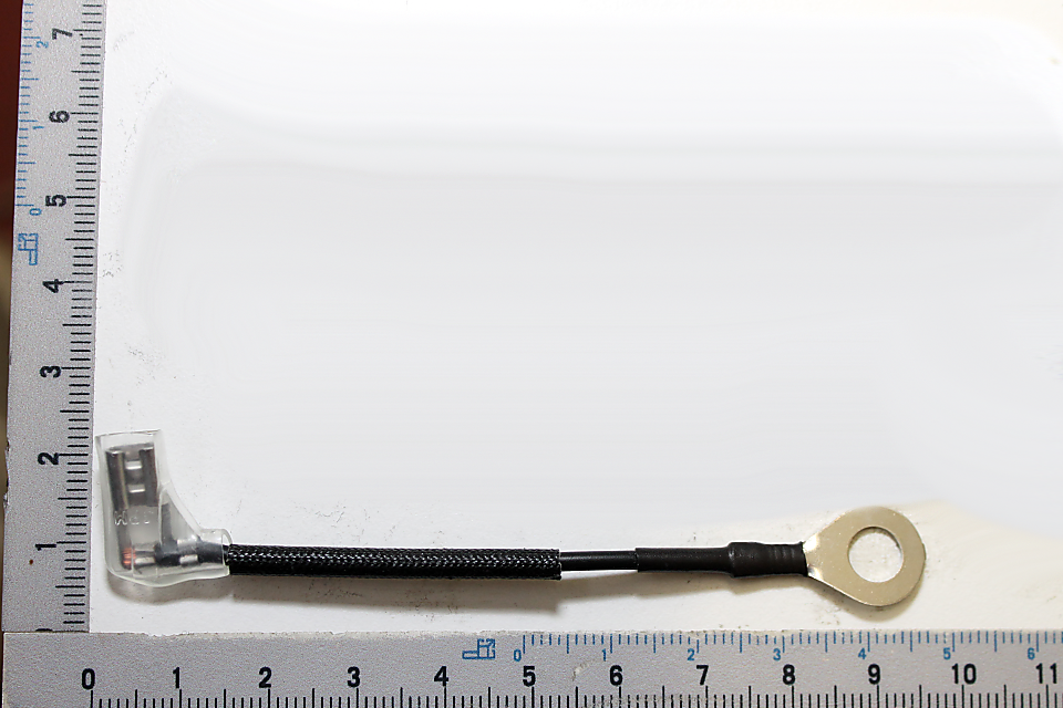 Ein Kabel mit einem Flachstecker und einer Ringöse, gemessen an einem Lineal von 75 mm Länge. Das Kabel liegt auf einem Lineal und wird von links nach rechts gezeigt.