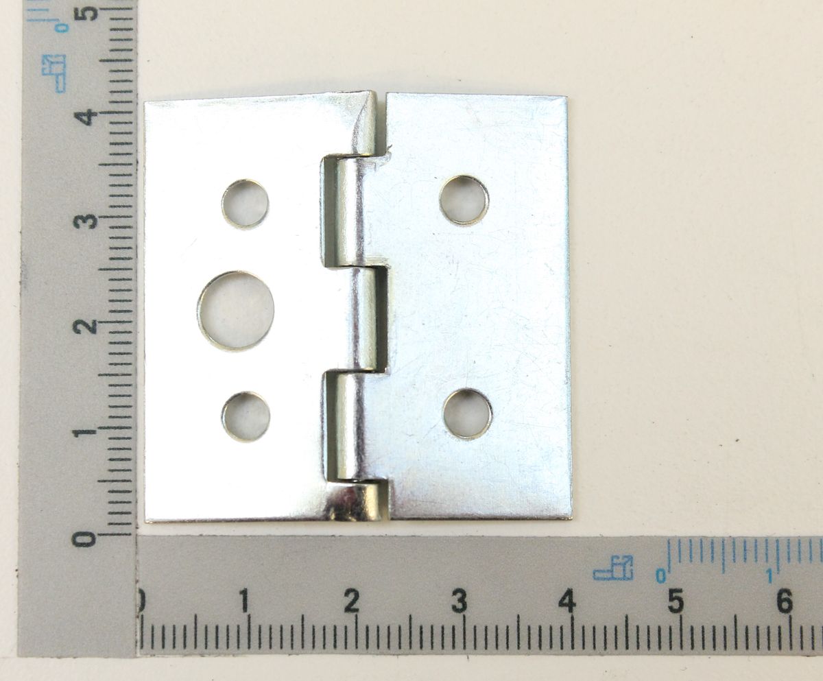 Ein Scharnier mit vier Löchern und einem zentralen Gelenk, von oben fotografiert. Das Scharnier hat eine quadratische Form und ist neben einem Lineal mit Zentimeter- und Millimeterskala platziert.