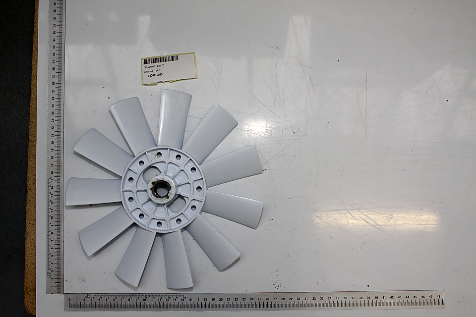 Ein grauer Lüfterrad mit acht Flügeln, auf einem weißen Hintergrund mit einem Lineal zur Größenmessung. Artikelnummer: intern_3906110013.