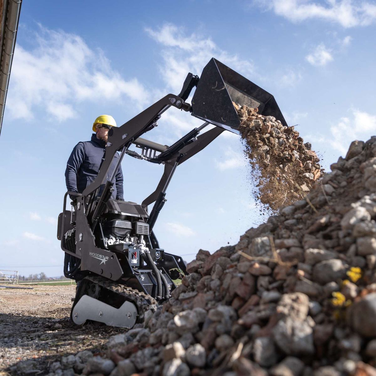 Kompaktlader mit Schaufel, die Materialien transportiert und ablegbar ist, im Einsatz mit einer Steigung von maximal 25°
