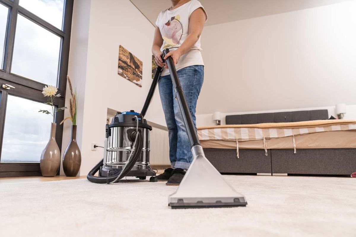 Eine Person reinigt mit dem Scheppach SprayVac20 einen Teppich. Der Staubsauger ist ein 5in1 Wasch-, Nass- und Trockensauger mit 20L Behälter.