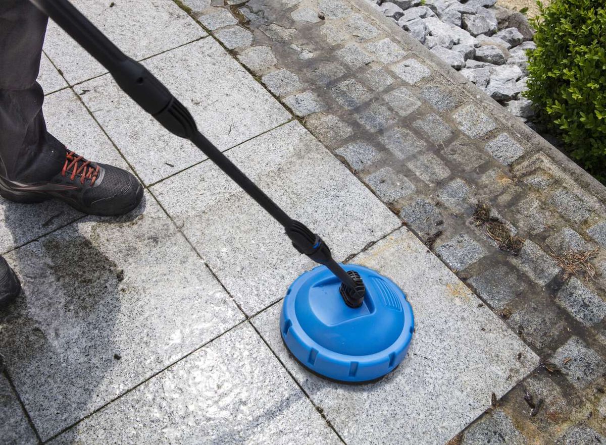 Elektro-Hochdruckreiniger HCE2200 von Scheppach im Einsatz auf einem Pflaster. Der Reinigungskopf ist aktiviert und reinigt die Steine.