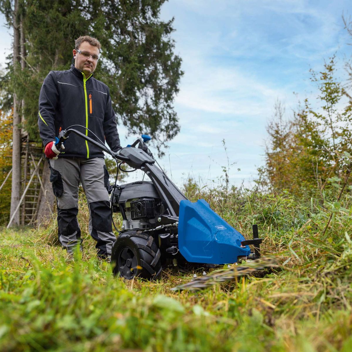 Mann betreibt Scheppach-Gräsmaschine mit Mulchfunktion in der Landschaft
