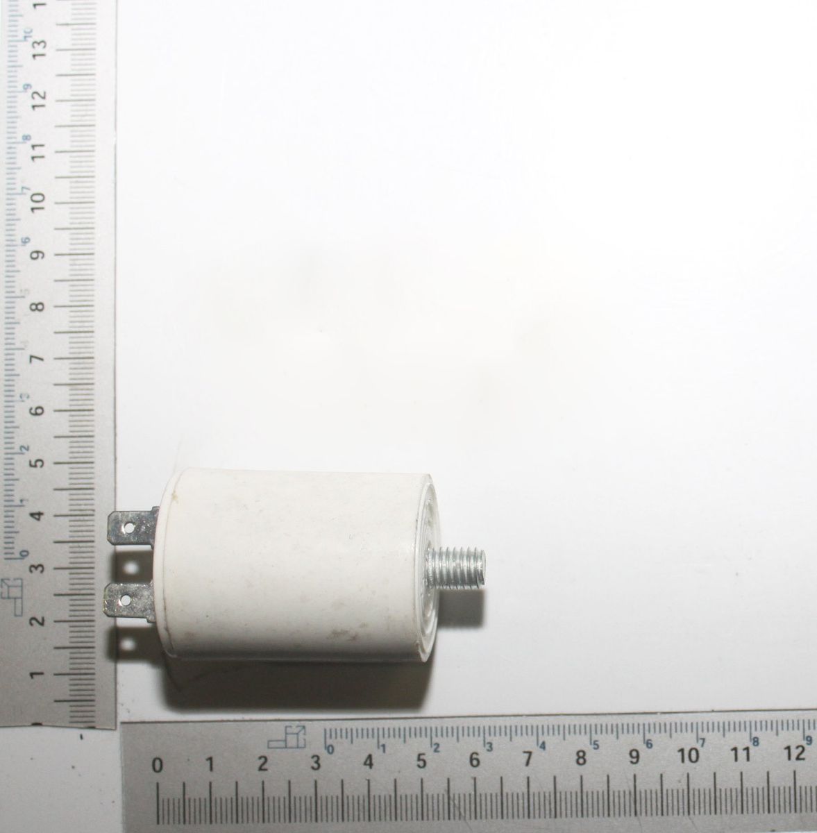 Ein Kondensator 6 µF von Scheppach, von der Seite fotografiert, mit einem Lineal zur Größenveranschaulichung.