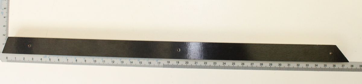 Eine schwarze Holzleiste mit drei Metallschrauben, von oben fotografiert.
