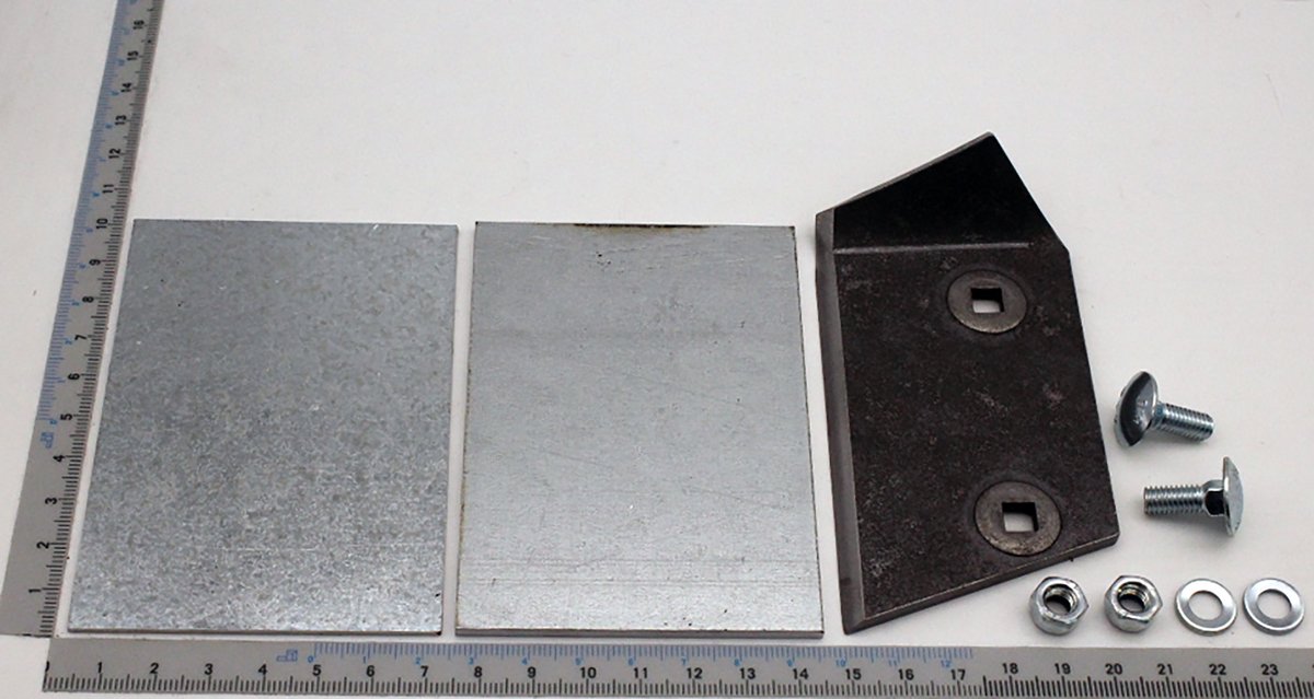 Ein Messinggegenmesser mit zwei Metallplatten und Befestigungsschrauben. Die Teile sind auf einem Lineal mit Millimeter- und Zentimeterangaben platziert.