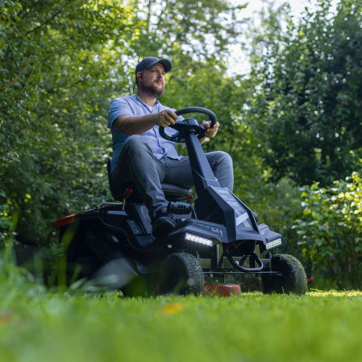 Mann fährt Scheppach-Benzin-Aufsitzrasenmäher MR225-61 auf dem Rasen