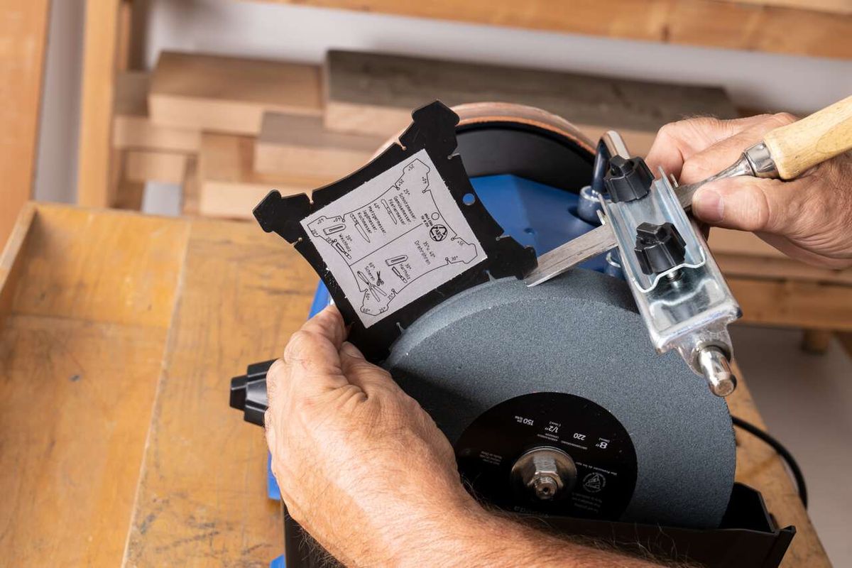 Scheppach TIGER 7000S wet bench grinder with instruction manual. A craftsman holds the device and attaches a component.