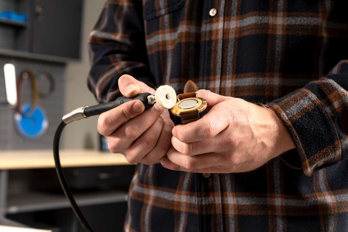 Ein Mann hält den flexiblen Wellenanschluss des Doppelschleifers HG35 von Scheppach in der Hand. Der Anschluss ist mit einer Schleifscheibe verbunden.