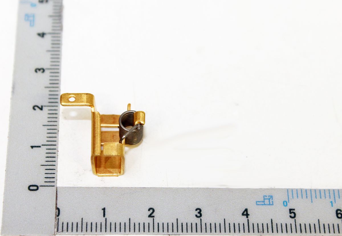 Kohlebürstenhalter neben einem Lineal zur Größenveranschaulichung. Der Kohlebürstenhalter ist von der Seite zu sehen.