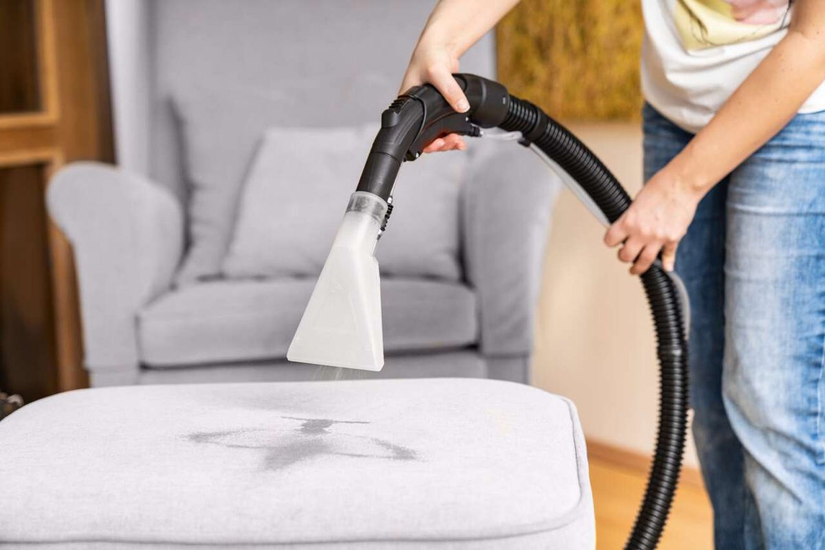 Personen verwenden Scheppach Sprüh- und Waschsauger zur Reinigung eines Sofas