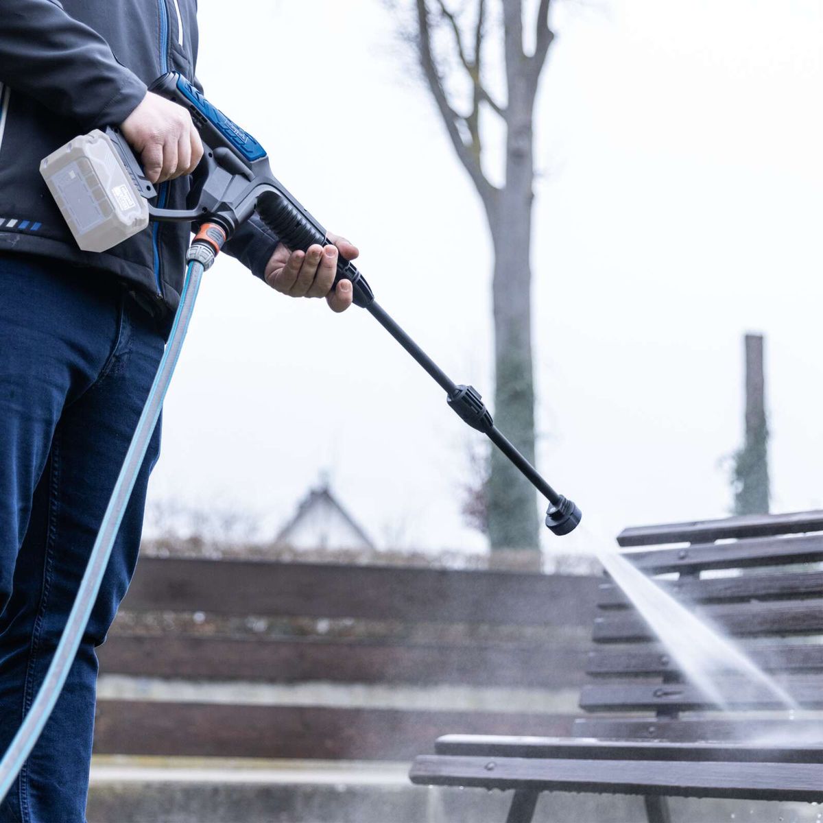 Person beim Reinigen mit Akku-Druckreiniger, Schlauch in Gebrauch