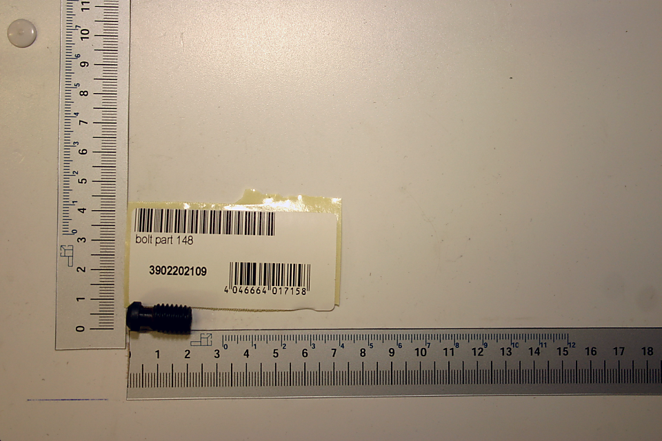 Ein Druckbolzen mit der Bezeichnung 'Druckbolzen Teil 148' und der Artikelnummer 3902202109. Der Bolzen liegt auf einem Lineal und ist von vorne zu sehen.