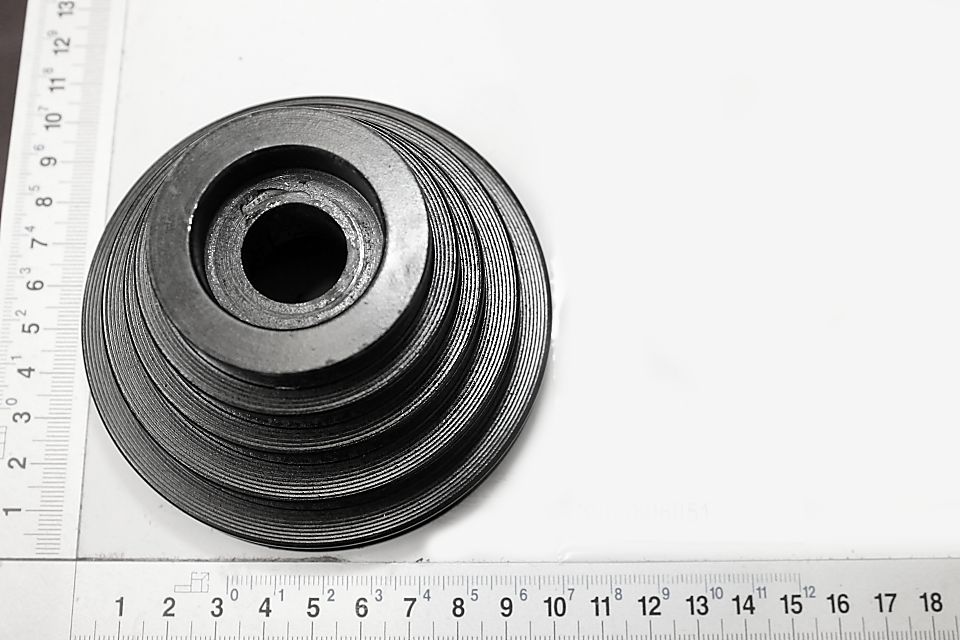 Riemenscheibe Ø100 von Scheppach. Die Scheibe hat konzentrische Rillen und einen zentralen Durchgang. Sie liegt auf einem Lineal mit Millimeter- und Zollskala.