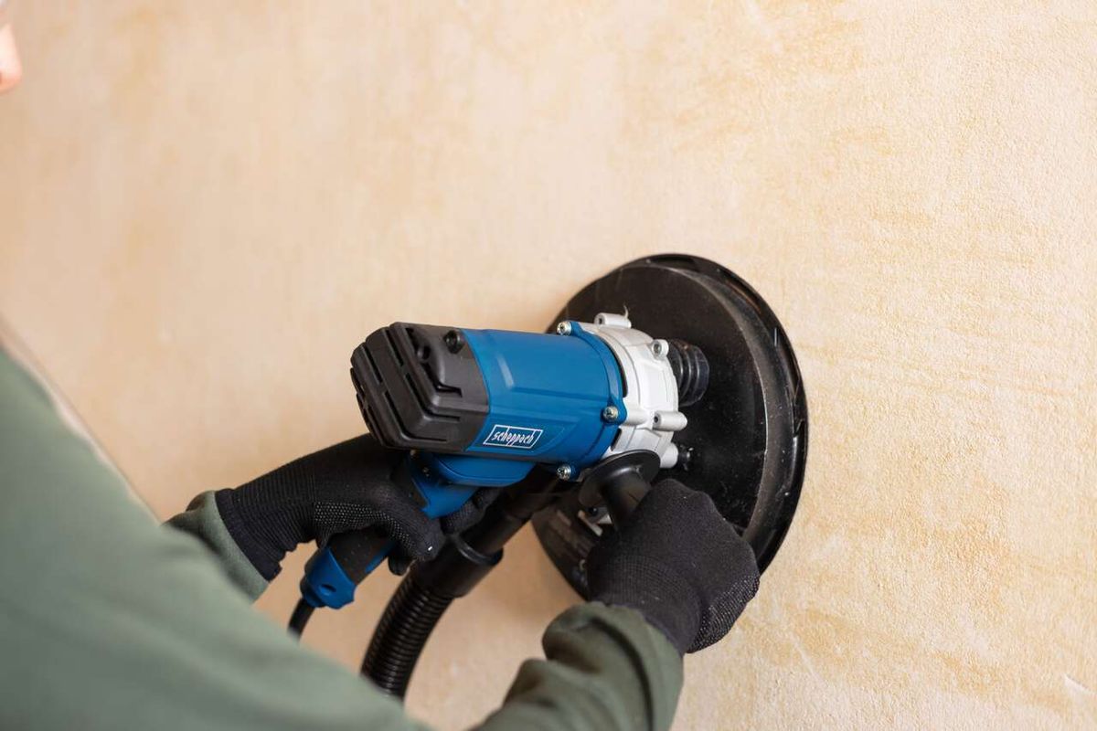 Wand- und Deckenschleifer DS200 von Scheppach im Einsatz. Die Maschine wird von einer Person an einer Wand verwendet. Der Schleifteller ist aktiv und berührt die Wand.