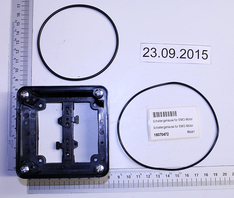 Ein Schaltergehäuse für EMG-Motor mit zwei Dichtungsringen und einem Maßstab zur Größenveranschaulichung.