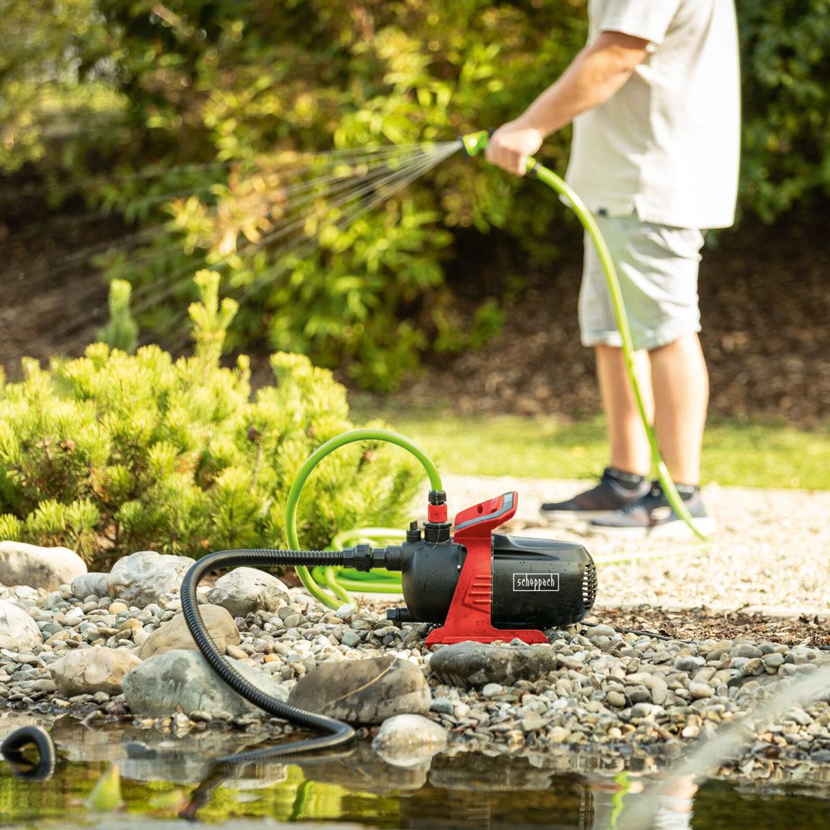 Elektro-Gartenpumpe Scheppach mit Wasserauslass für Bewässerungssystem, gepflückt auf einem Steinboden