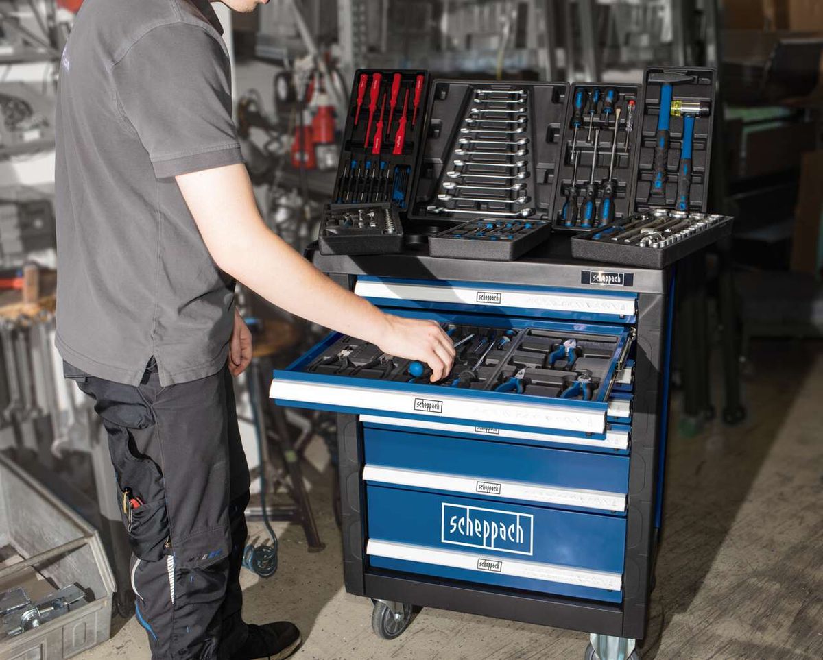 Ein Mann öffnet eine Schublade des Werkstattwagens TW1000 von Scheppach. Oben liegen verschiedene Werkzeuge in Sortierkästen.