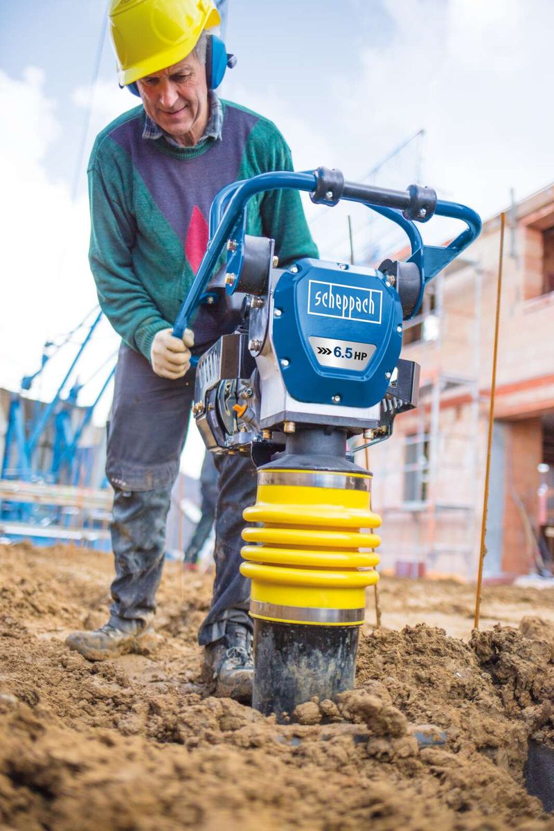 Ein Arbeiter bedient den Vibrationsstampfer VS1000 von Scheppach auf einer Baustelle. Der Stampfer hat 6,5 PS und ist im Einsatz zu sehen.