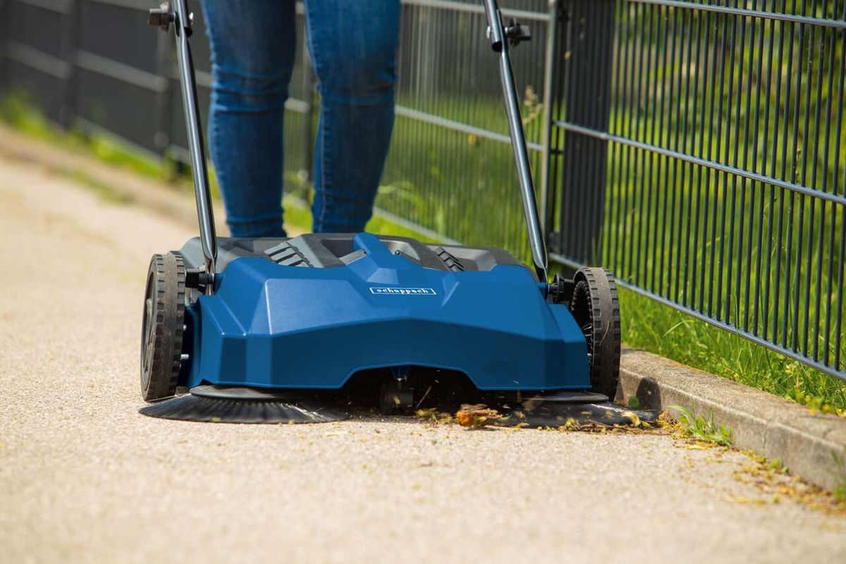 Scheppach Kehrmaschine Trike-S mit Fußgängeraufsatz, die eine Straße reinigt
