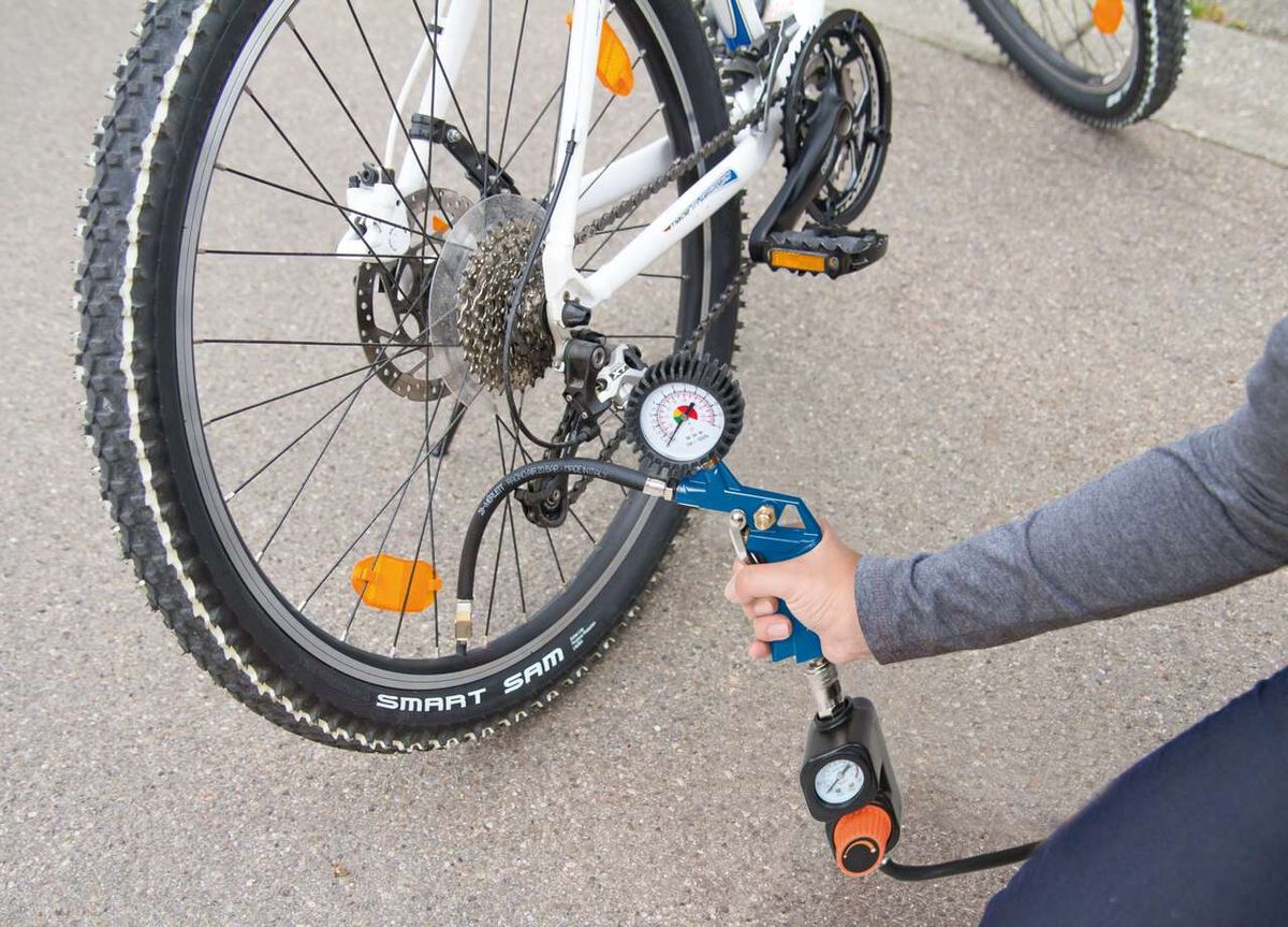 Ein Scheppach-Kompressor wird verwendet, um den Reifendruck eines Fahrrads zu überprüfen. Der Kompressor ist mit einem Druckmesser ausgestattet, der den aktuellen Druck anzeigt.