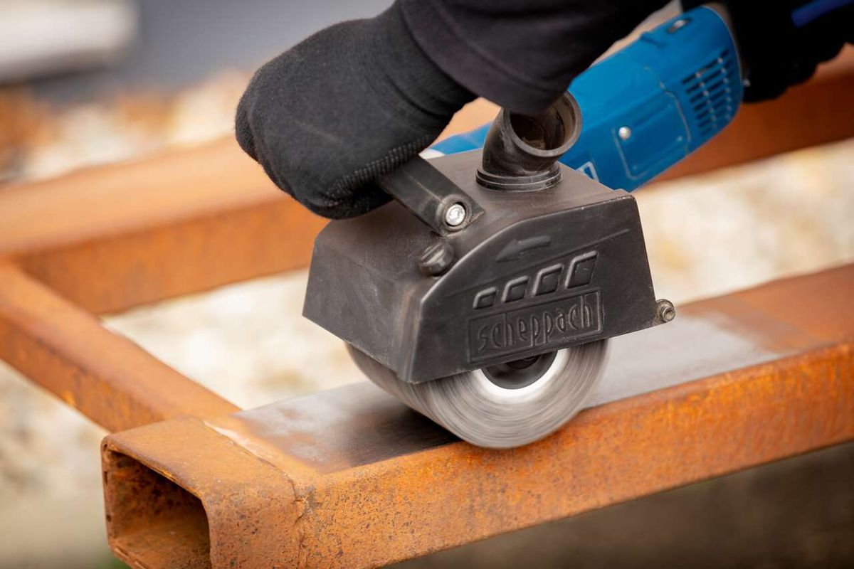 Siliziumkarbidbürste von Scheppach im Einsatz an einer MRS1300 Satiniermaschine. Die Bürste wird von einem blauen Elektrowerkzeug gehalten und bearbeitet ein Metallteil.