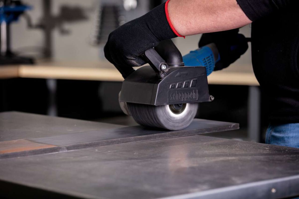 Scheppach Siliziumkarbidbürste im Einsatz an einer MRS1300 Satiniermaschine. Die Bürste wird von einer Person mit Schutzhandschuhen geführt.