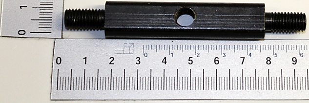 Ein Gelenkbolzen mit Gewinde an beiden Enden, daneben eine Messskala zur Größenveranschaulichung. Der Bolzen wird von oben gezeigt.