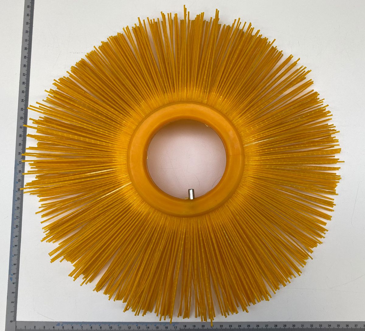 Bürste innen mit gelben Borsten, von oben fotografiert, mit Maßstab im Hintergrund.