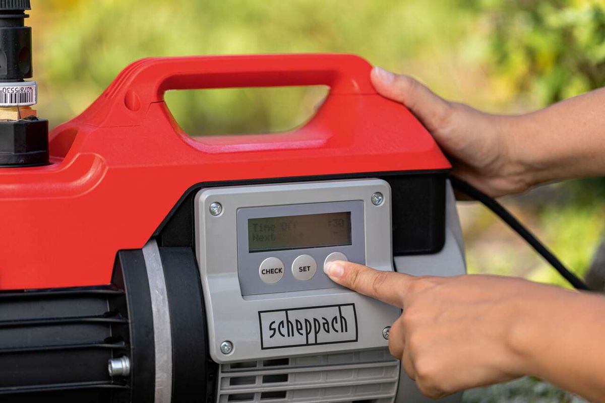 Hauswasserautomat GP1000 Jet LCD Scheppach mit Bedienfeld, eine Hand drückt auf den SET-Knopf.